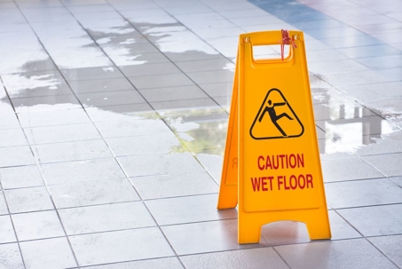 A yellow caution sign on a wet tile floor.