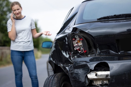 Woman looking at her car after an accident