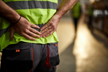 Image of a man with a high visibility vest holding their back